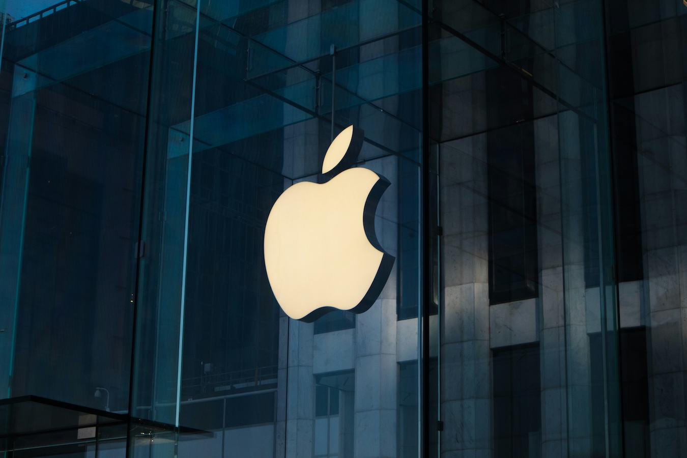 Lit-up Apple logo on glass storefront at night – iconic minimalist branding showcasing simplicity and global recognition in logo design.