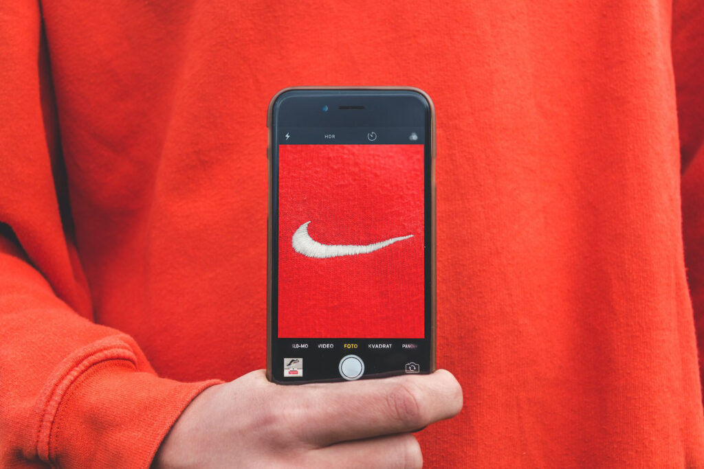 Artwork for branding article – Nike logo on red iPhone highlighting how branding is more than just a logo. Written by David Payne, a freelance graphic designer in Shrewsbury.