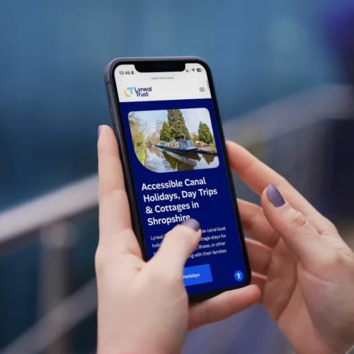 Woman holding iPhone displaying the Lyneal Trust accessible website design