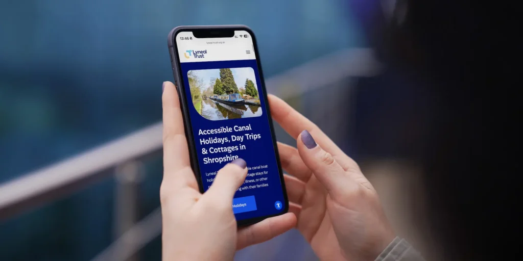 Woman holding iPhone displaying the Lyneal Trust accessible website design