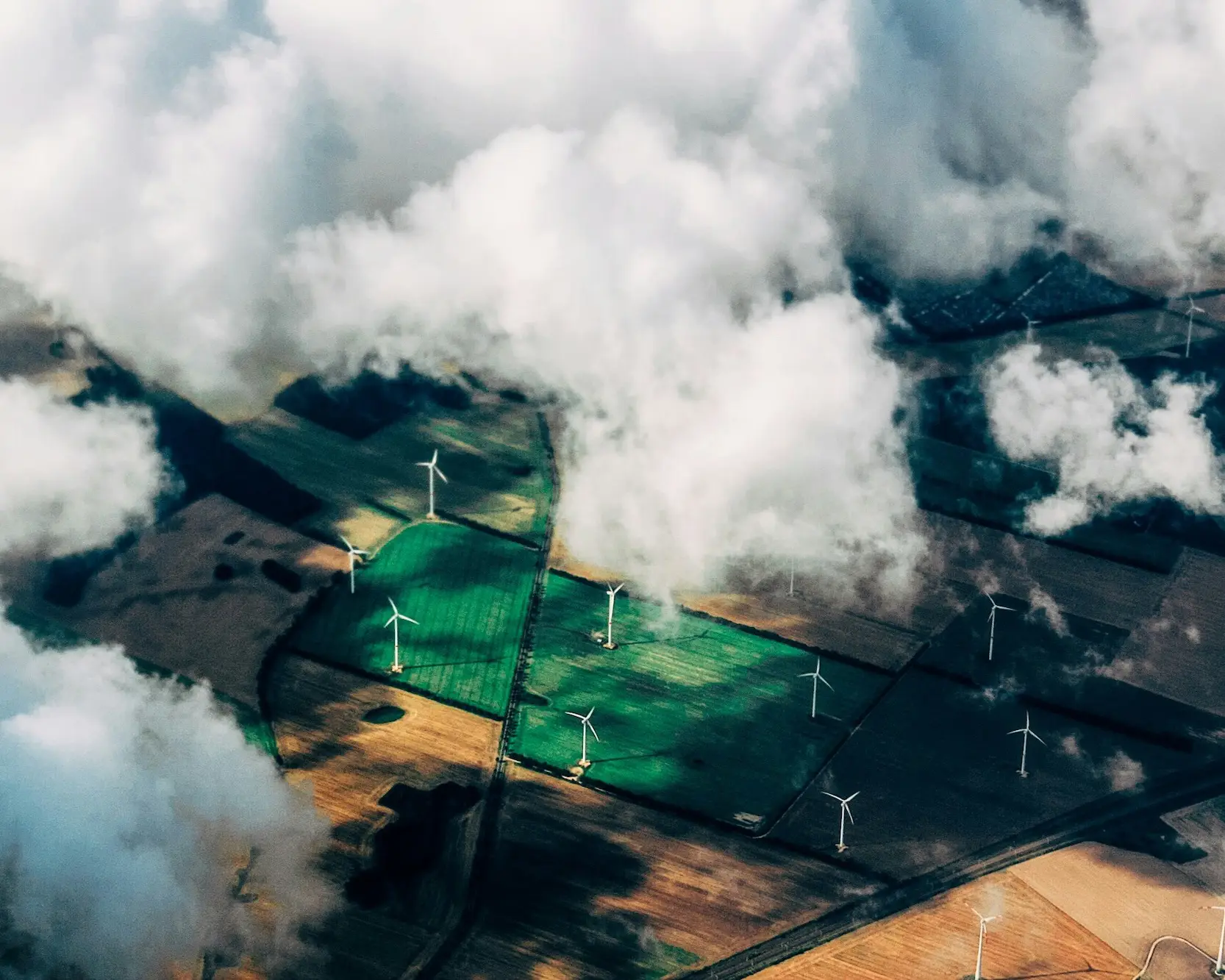 Field of wind turbines from above clouds – renewable energy powering Studio Payne web hosting