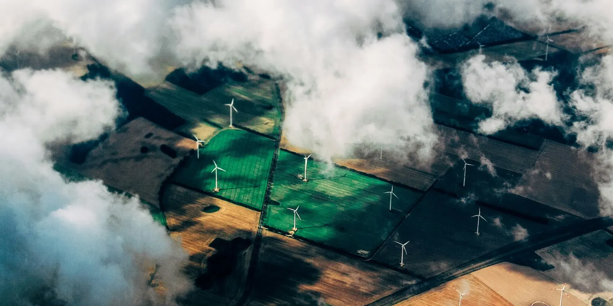 Field of wind turbines from above clouds – renewable energy powering Studio Payne web hosting