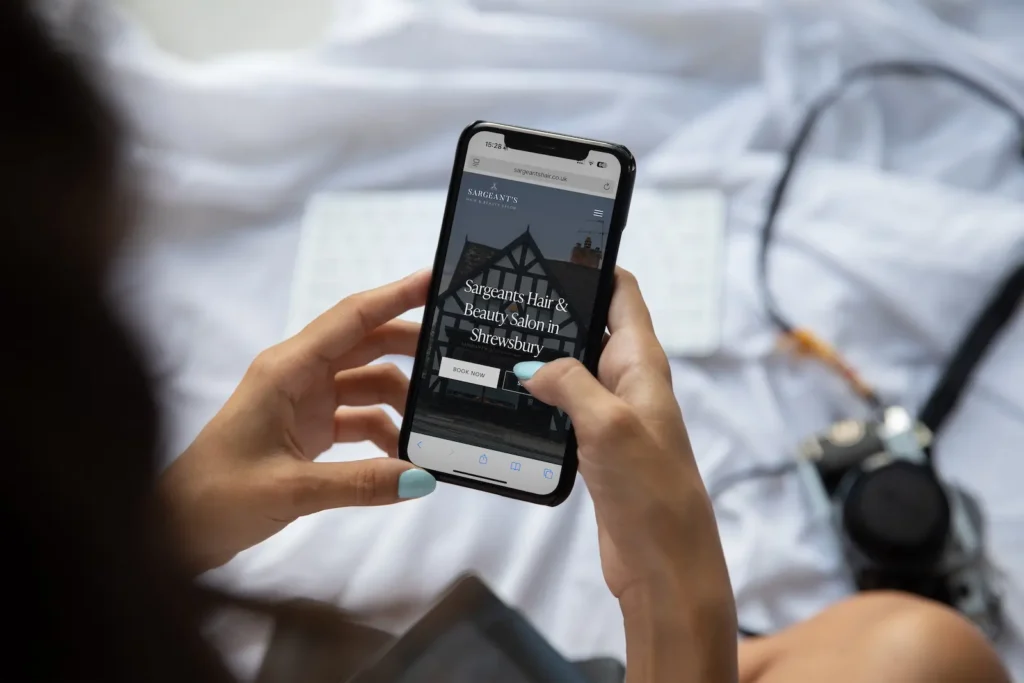 Mobile-friendly website design for Shrewsbury hair salon displayed on iPhone held by woman