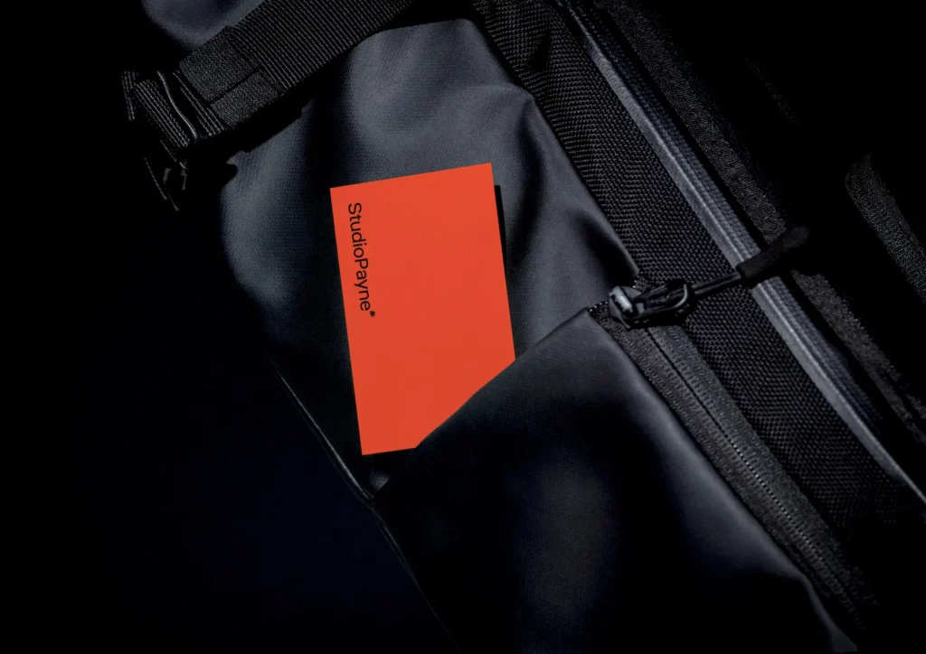 Studio Payne logo printed on orange business card inside black rucksack, branding design detail